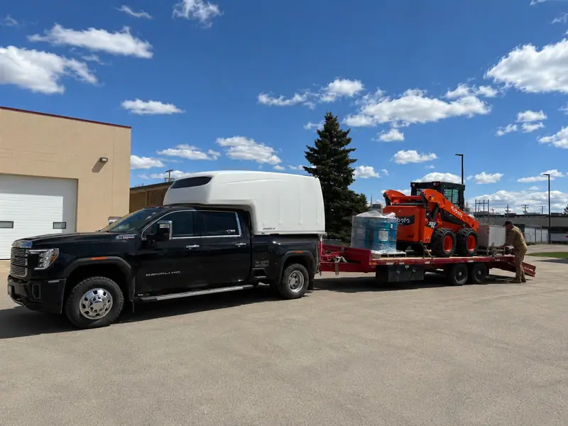 Arrow truck towing a trailer with a compact excavator