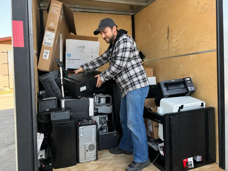 Arrow technician loading retired computers into a trailer for recycling