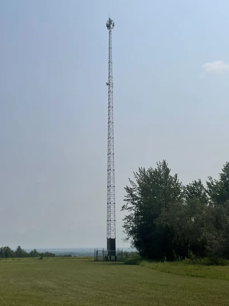 An Arrow lattice tower rising over a hayfield